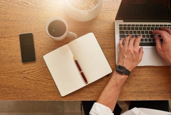 A person sitting at a desk with a laptop and notebook.